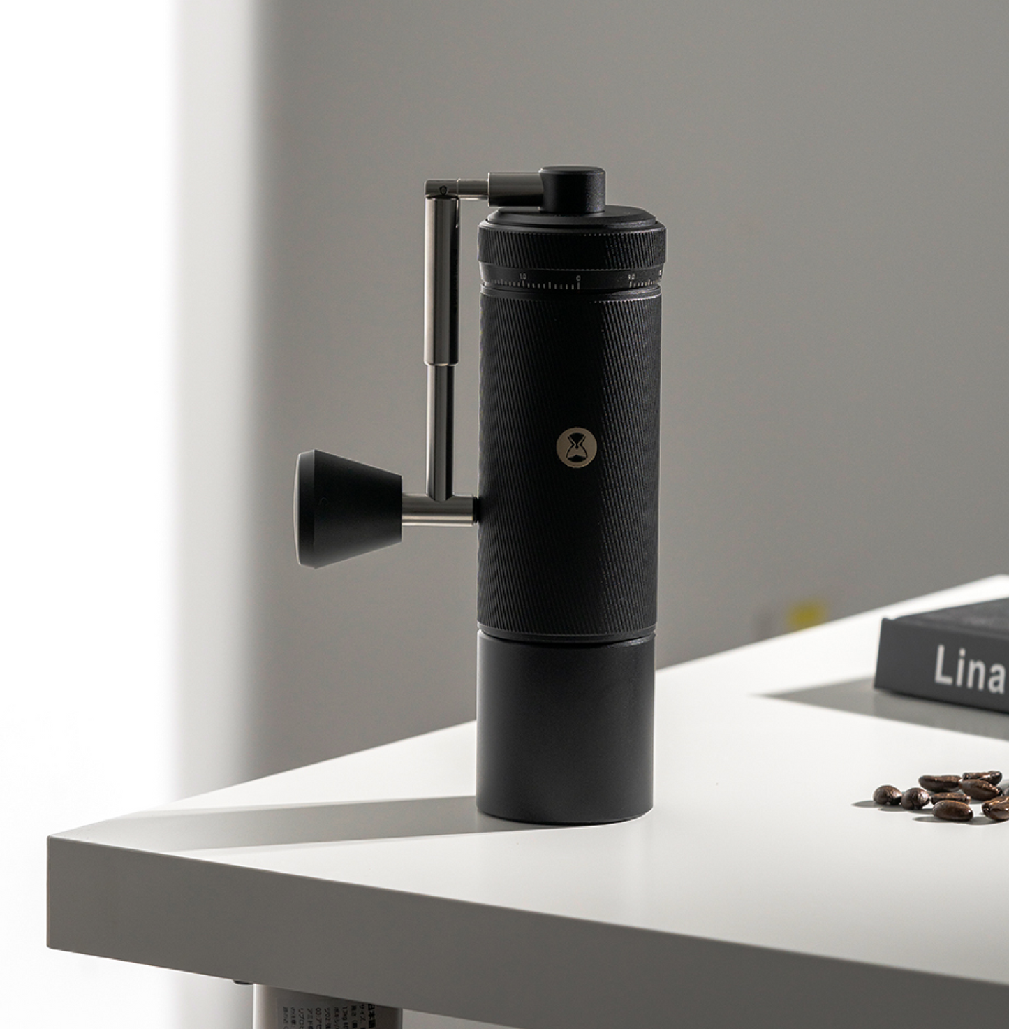 Timemore Chestnut S3 Handkaffeemühle mit einziehbarer Kurbel auf weißem Tisch neben Kaffeebohnen