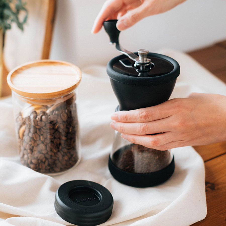 Hario Skerton N Handkaffeemühle mit Keramikmahlwerk befüllt mit Kaffeebohnen für frischen Mahlkaffee zu Hause oder unterwegs.
