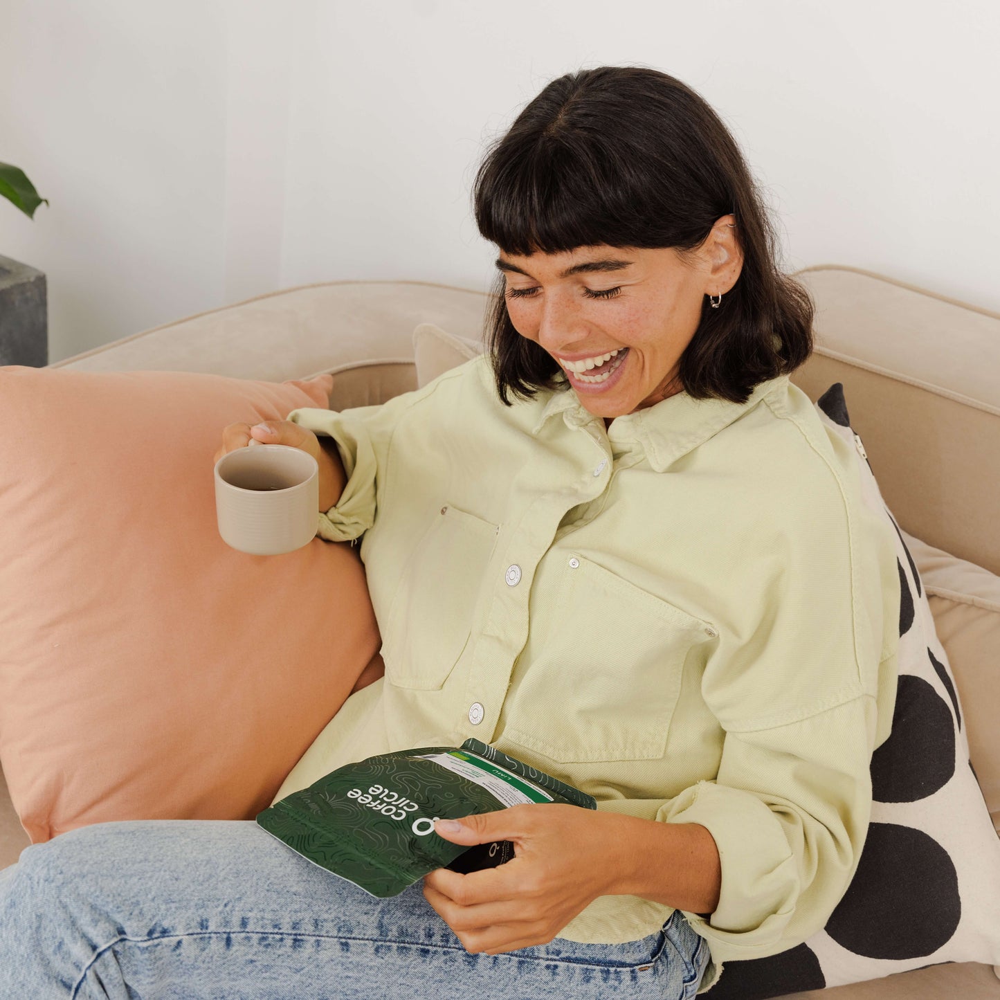 Frau entspannt mit Kaffee und Paket vom nachhaltigen Geschenkabo für besondere Kaffeemomente