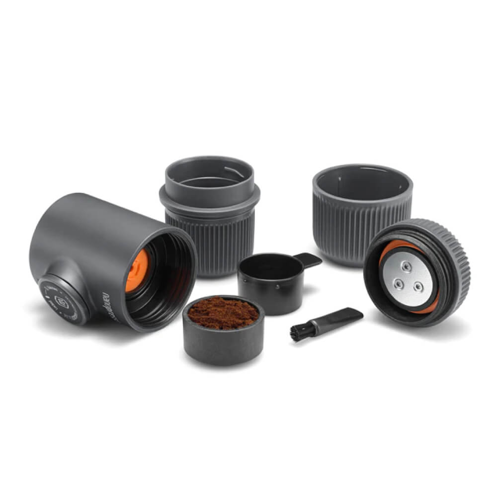 Wacaco Nanopresso Espressozubereiter zerlegt mit Kaffeesatz, Tassen und Reinigungspinsel für Outdoor-Espresso.
