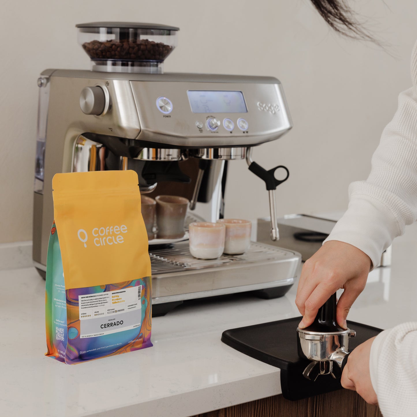 Espresso Cerrado in gelber Packung neben Espressomaschine mit frisch gemahlenem Kaffee und Tamper.