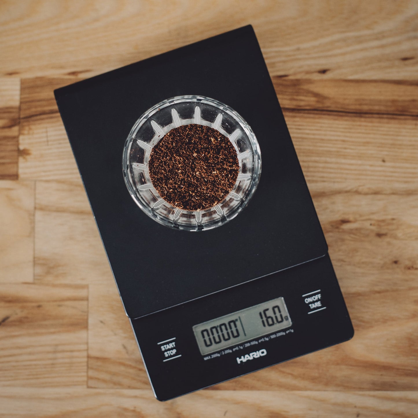 Hario V60 Drip Scale - Waage mit Stoppuhr zeigt 16 Gramm Kaffeepulver auf schwarzer Waage.